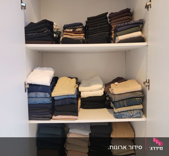 בגדים מקופלים בארון לבן בשלושה מדפים